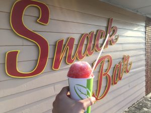 cherry snowball in front of snack bar sign at bengies drive-in theatre